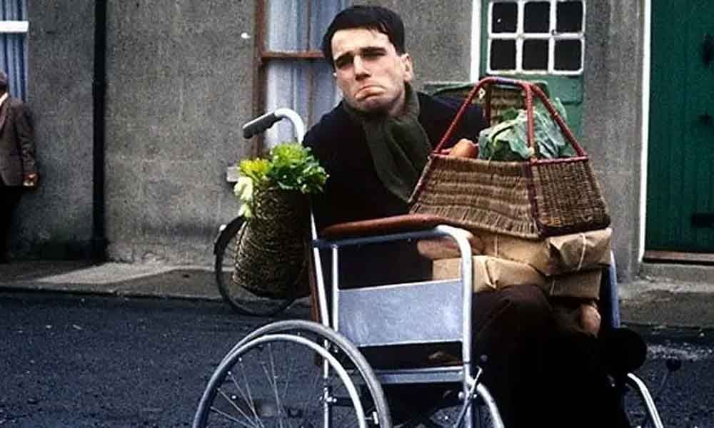 Daniel Day-Lewis sitting in a wheelchair during filming of 'My Left Foot'