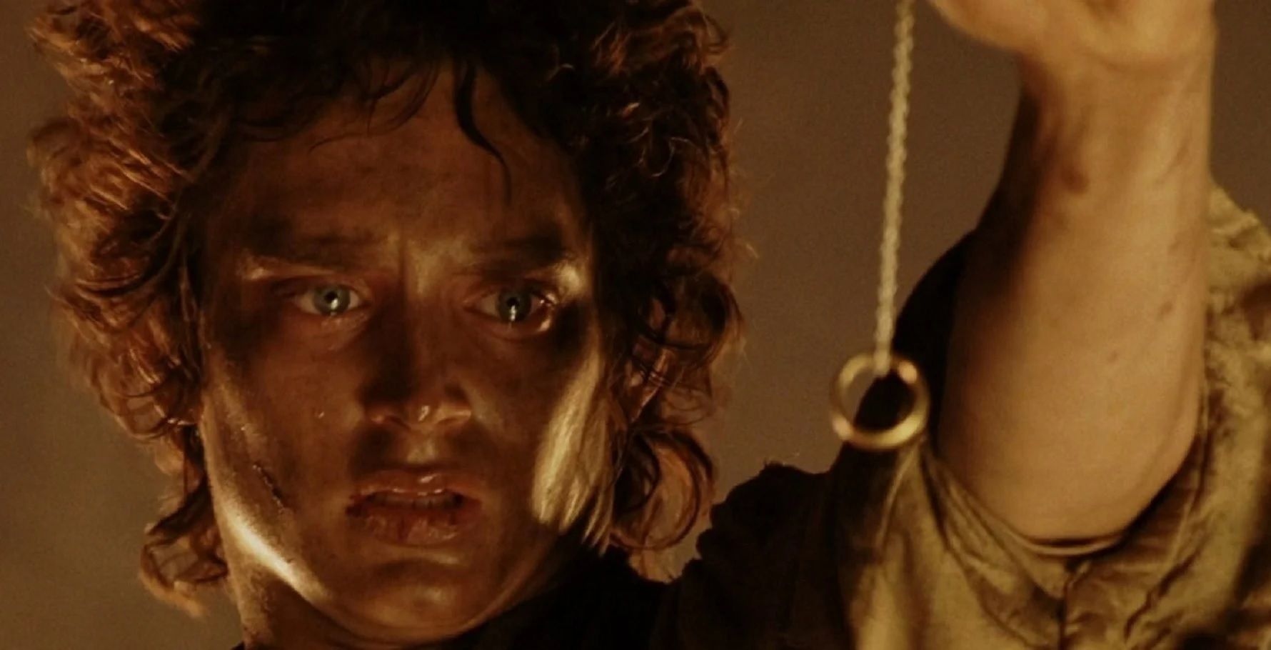 Elijah Wood as Frodo Baggins holding the One Ring