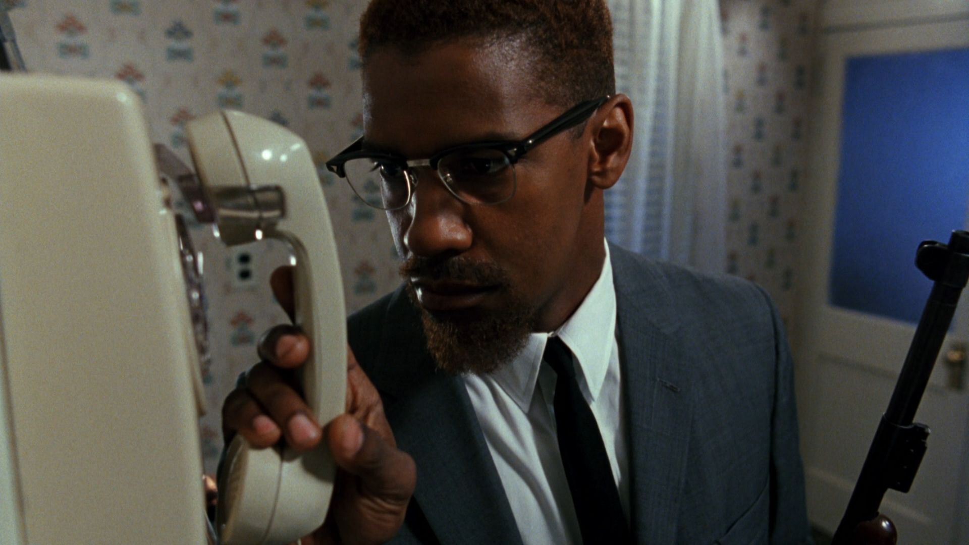 Malcolm X hangs up the phone in his kitchen