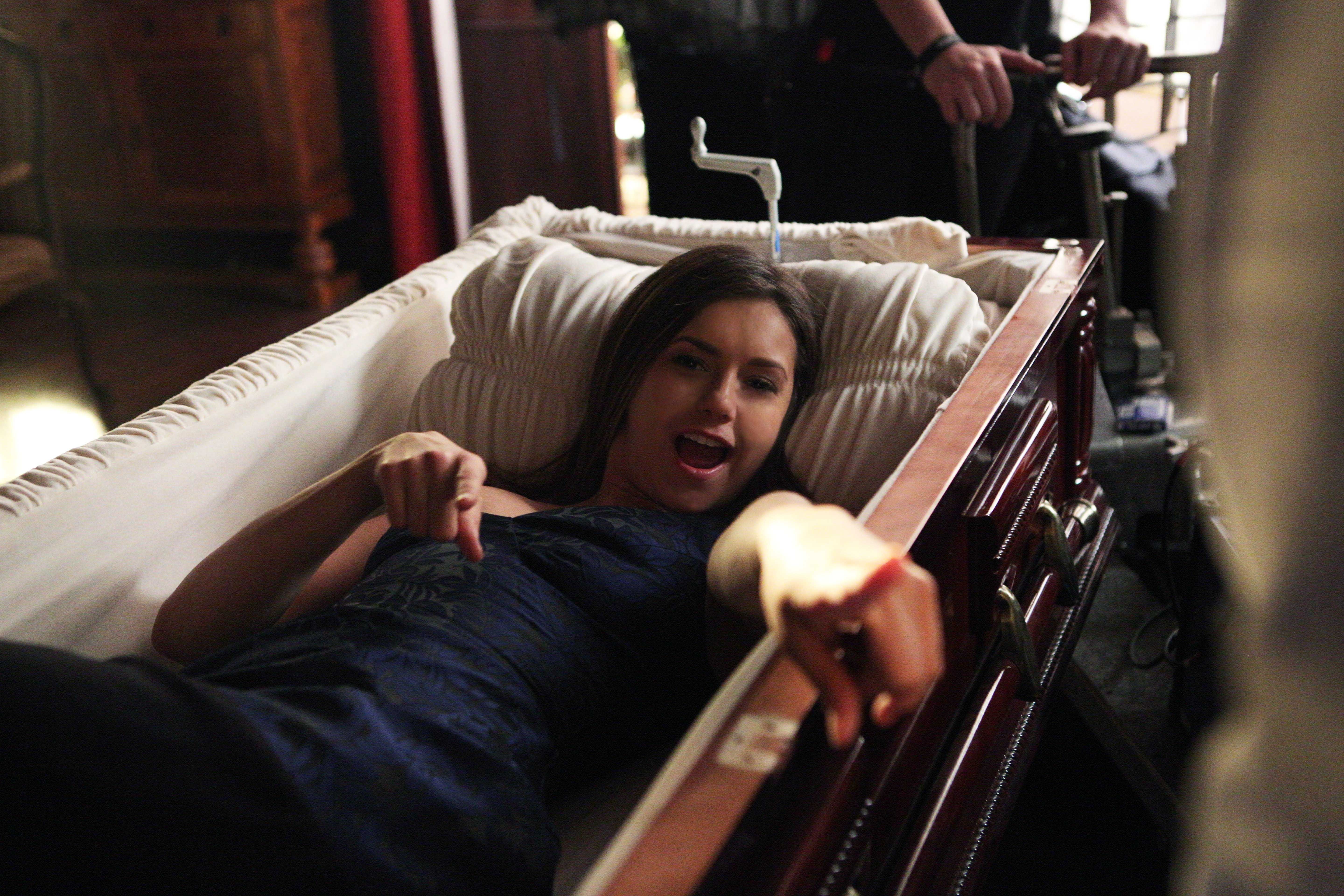 Nina Dobrev lying in a coffin on the set of The Vampire Diaries.