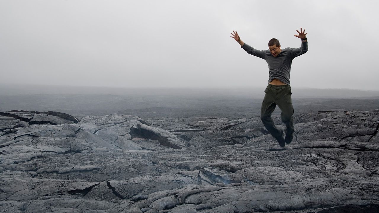 Bear Grylls jumping near a volcano on Man vs Wild.