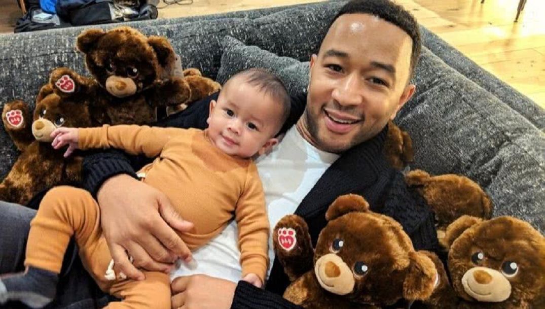 John Legend with son Miles and teddy bears lying on couch