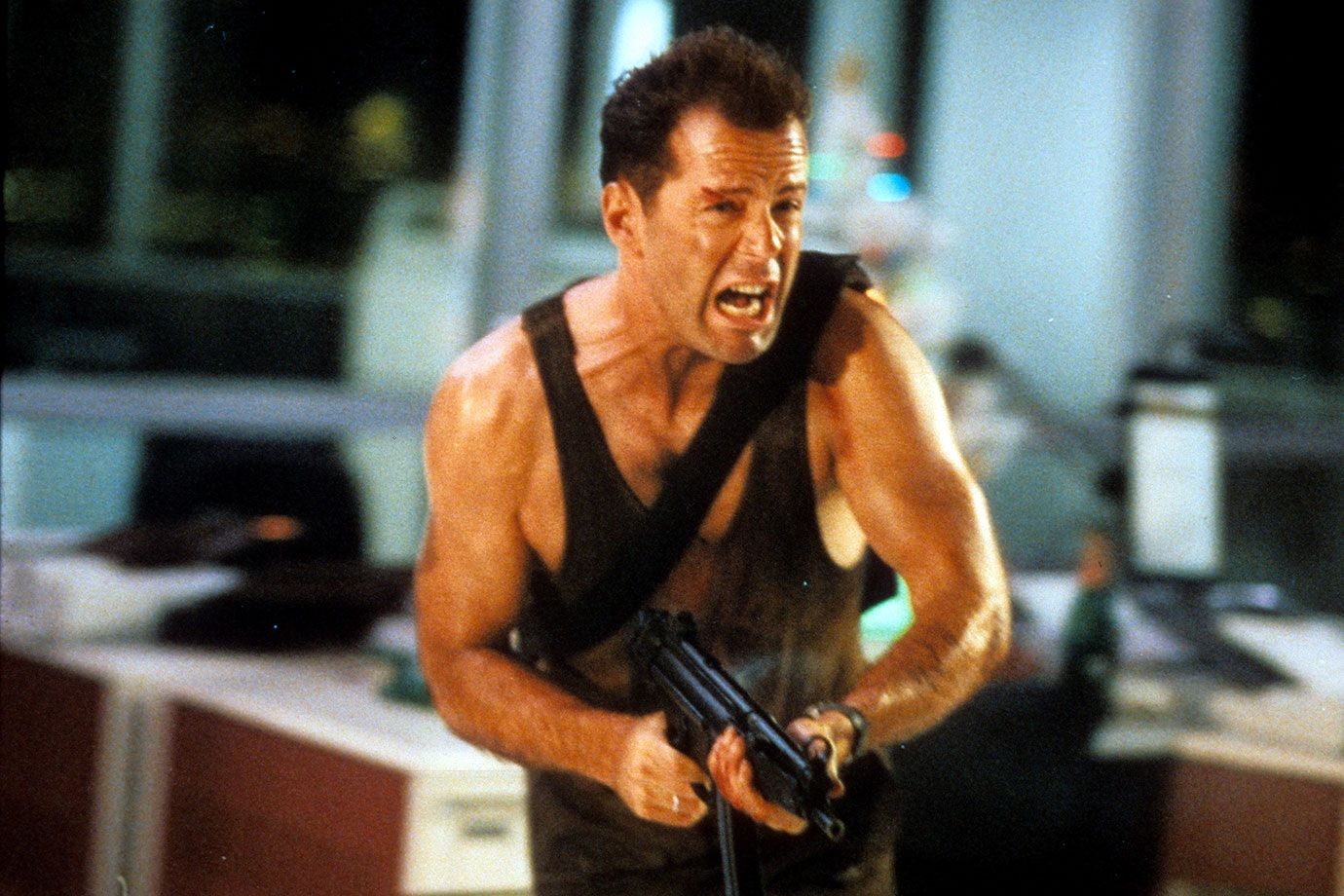 Bruce Willis shooting a gun in Die Hard.