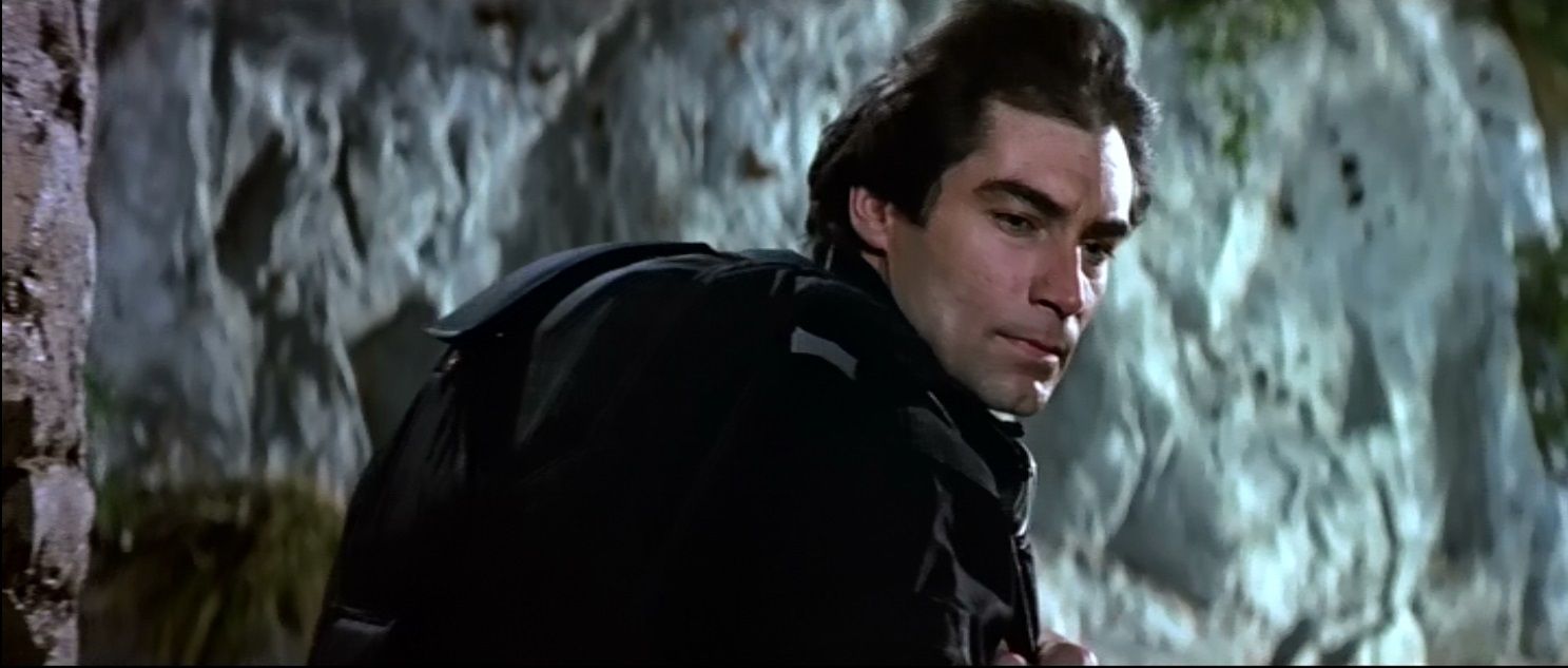 Timothy Dalton as Bond climbing a cliff