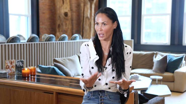 Jules Wainstein indossa una camicia bianca e jeans in piedi in casa