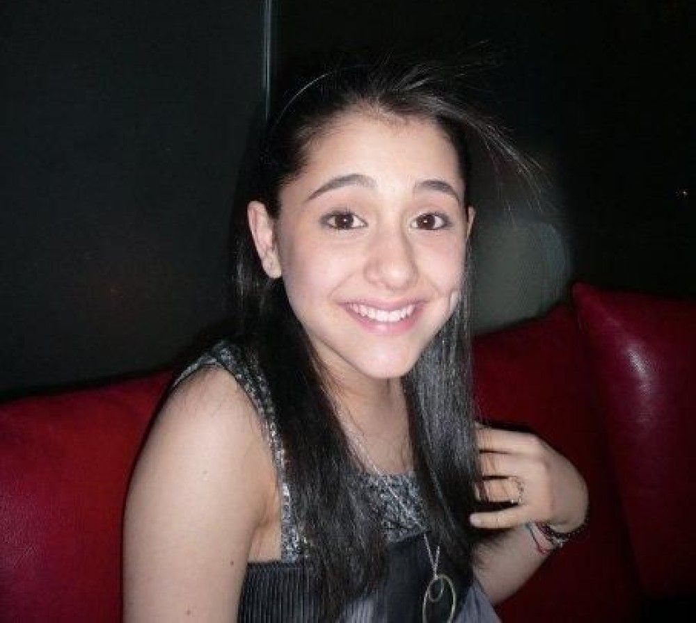 Young Ariana Grande with black hair on red sofa