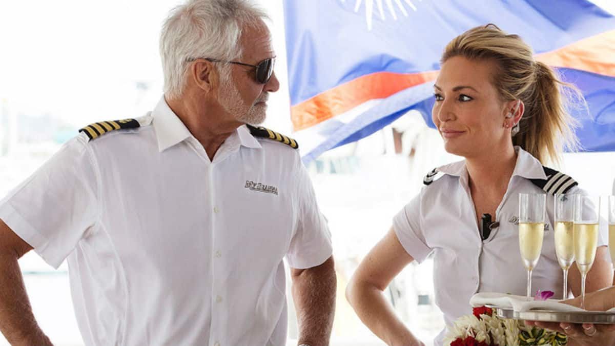 captain lee rosbach standing next to kate chastain on boat while filming bravo reality tv show below deck