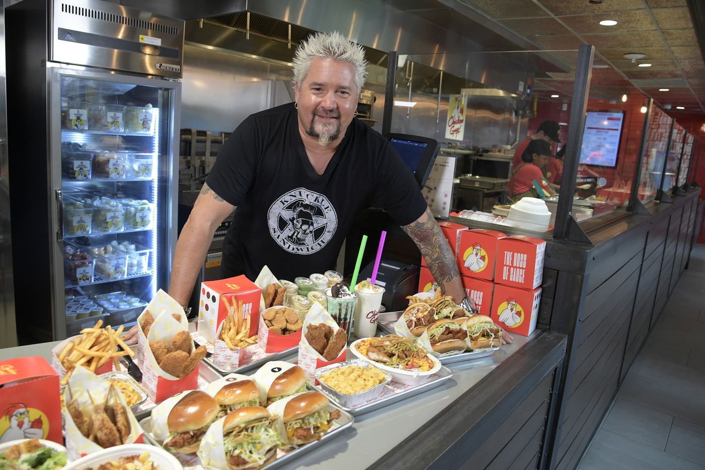 guy fieri standing behind chicken and fries in containers at chicken guy restaurant