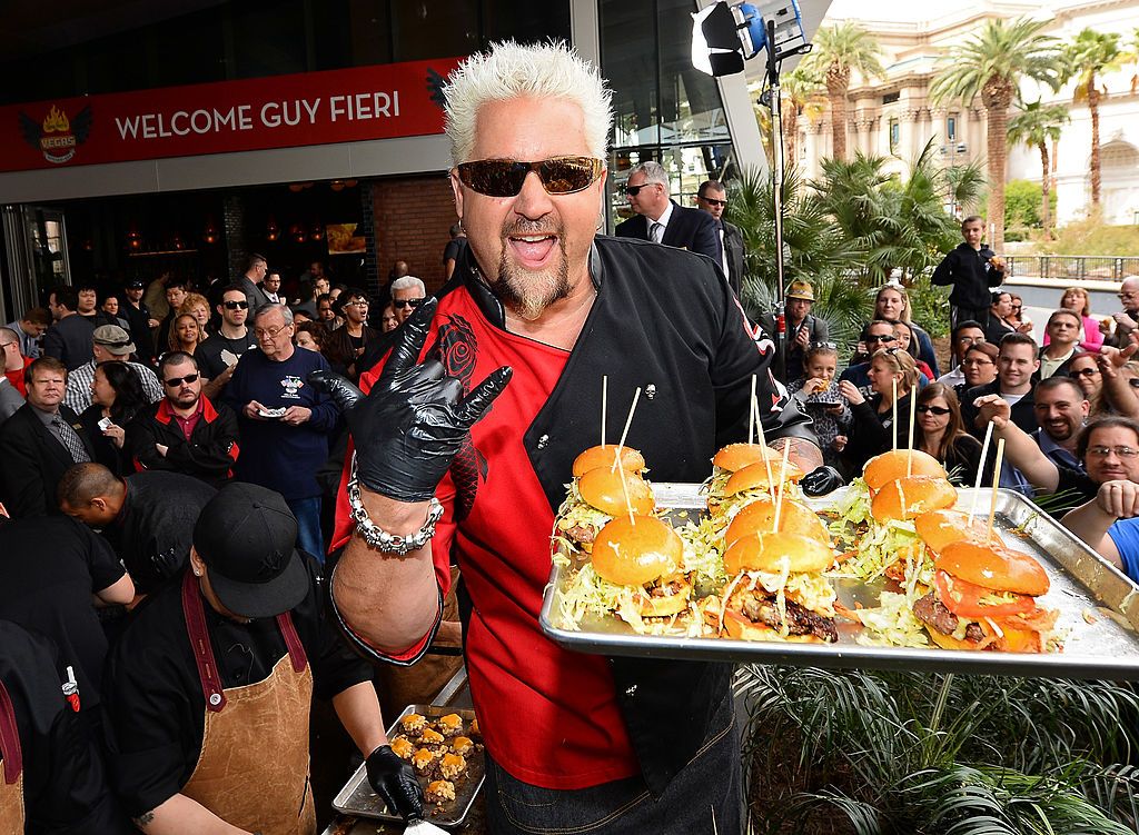 guy fieri holding tray of sandwiches at event