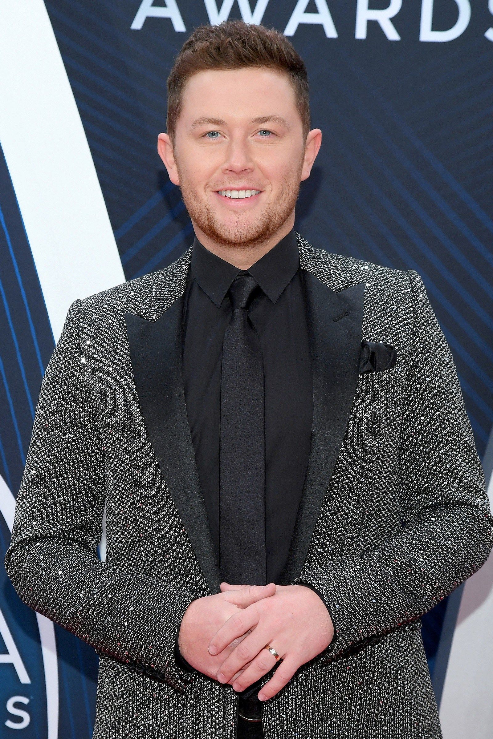 Scotty McCreery wearing a tweed blazer over a black shirt and neck tie