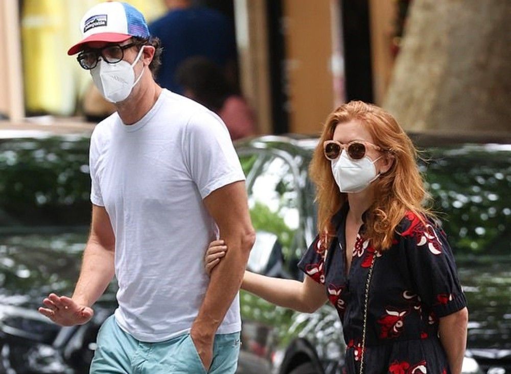 Isla Fisher and Sacha Baron Cohen walking wearing masks