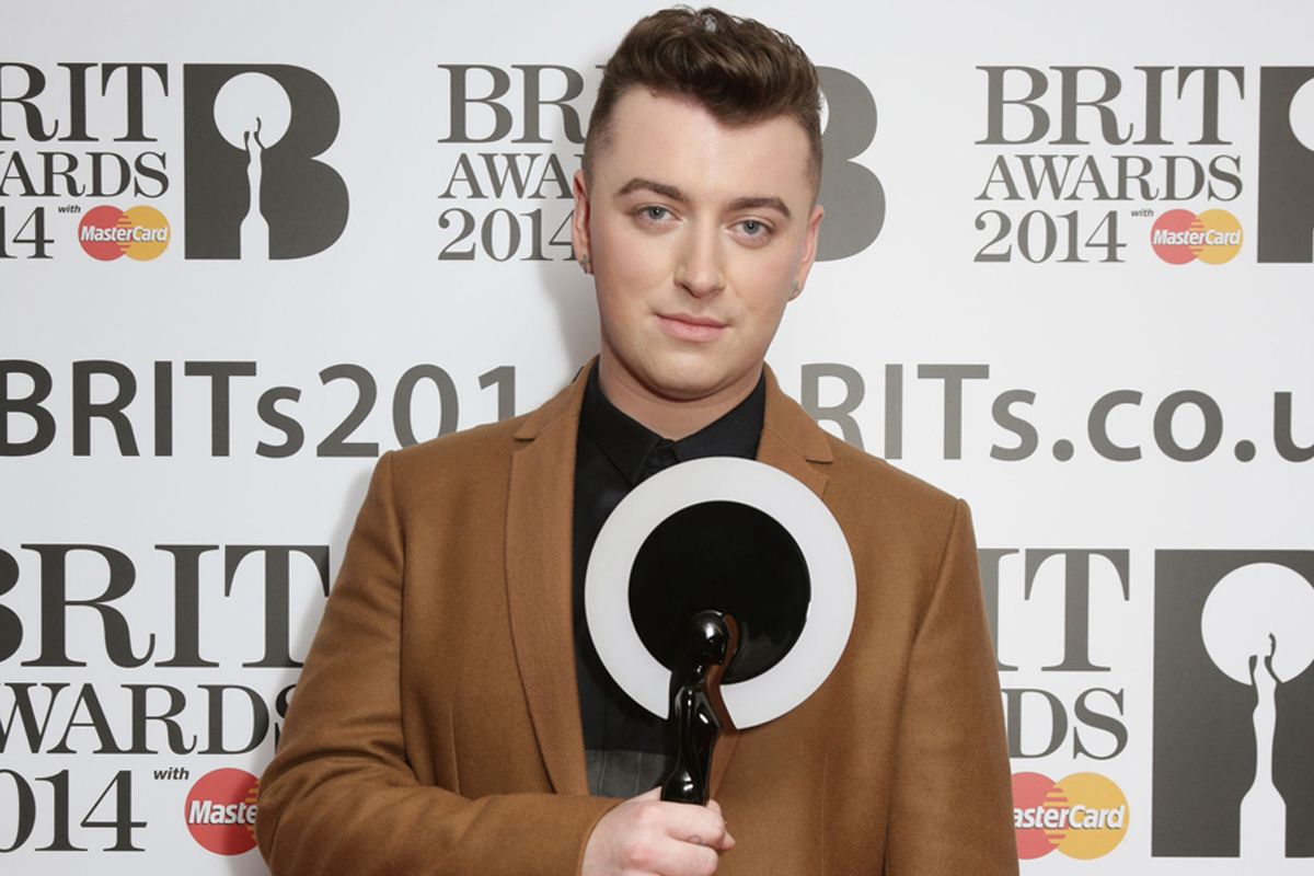 Sam Smith holding Brit Award trophy infront of logo wall