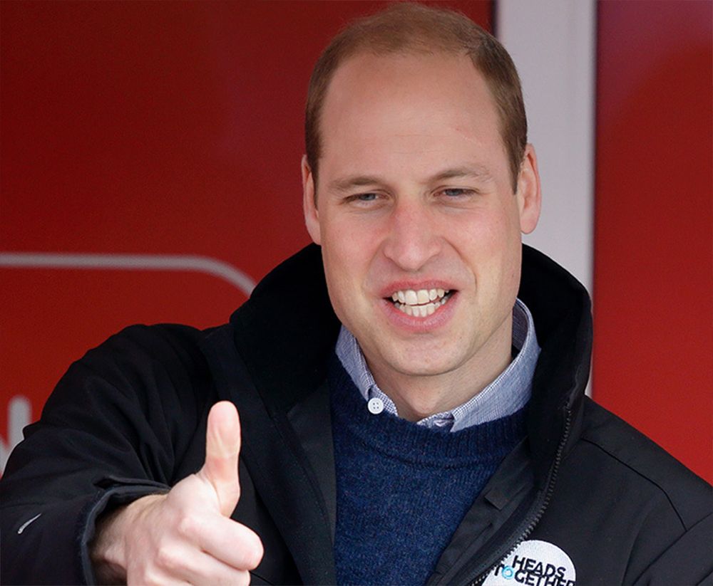 Prince William thumbs up smiling red background