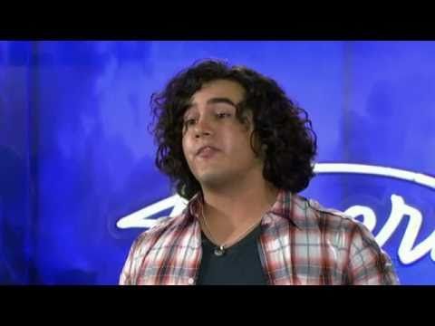 Chris Medina singing at his American Idol audition wearing a red and white plaid shirt.