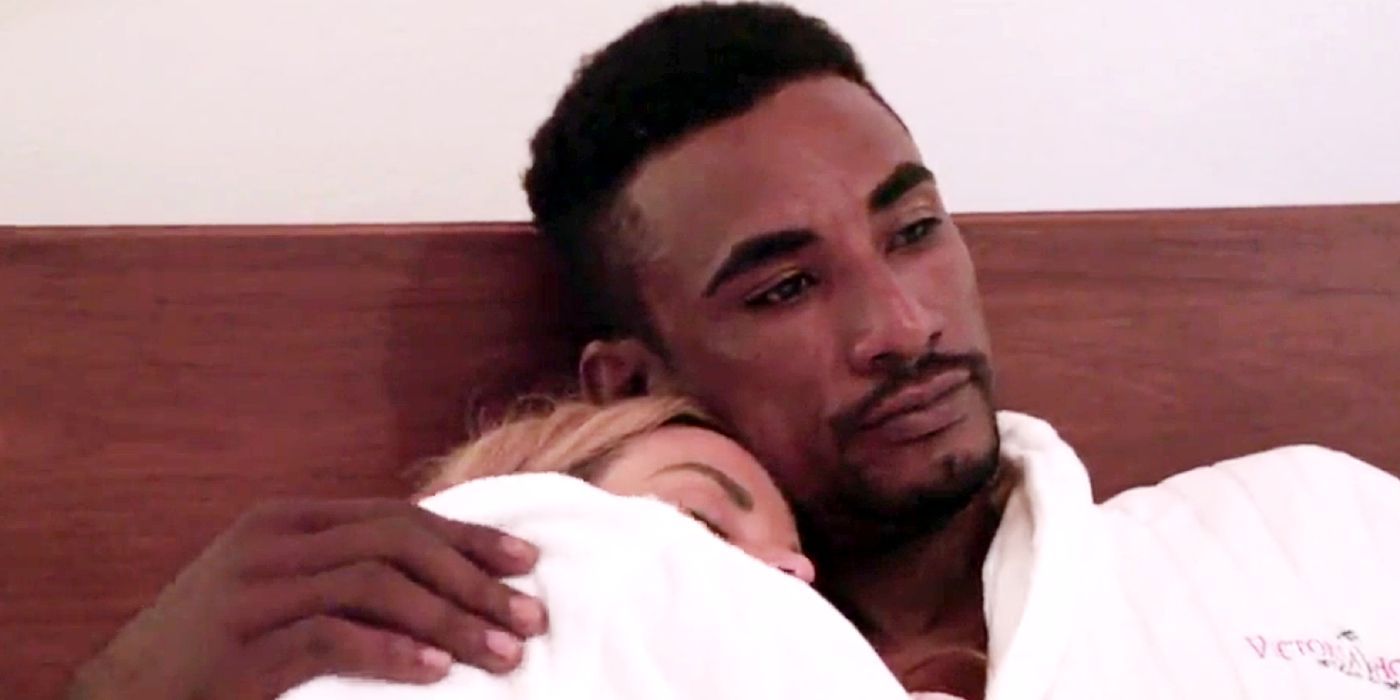 Stephanie cuddling with Harris in bed and they're both wearing white robes.