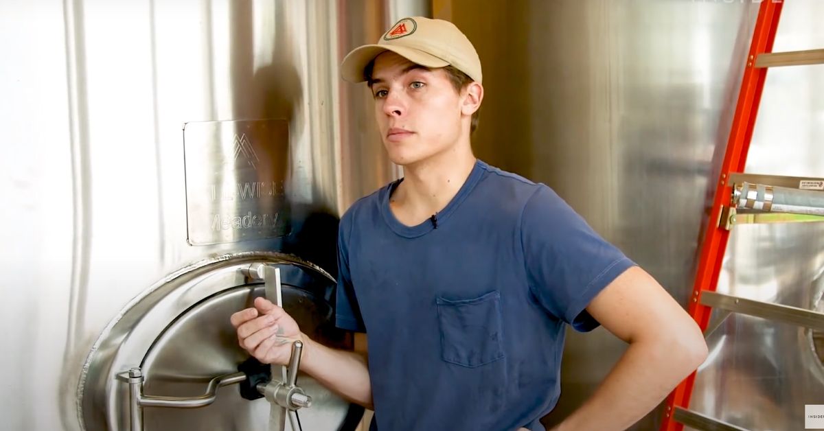Dylan Sprouse wearing a tan hat and blue shirt at his mead brewery.