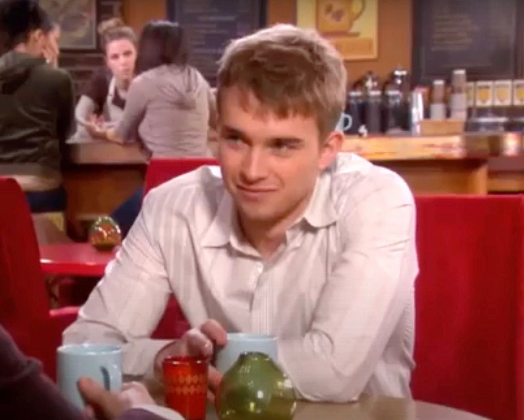 Will smiling and putting his arms on a table at a diner in Days Of Our Lives.