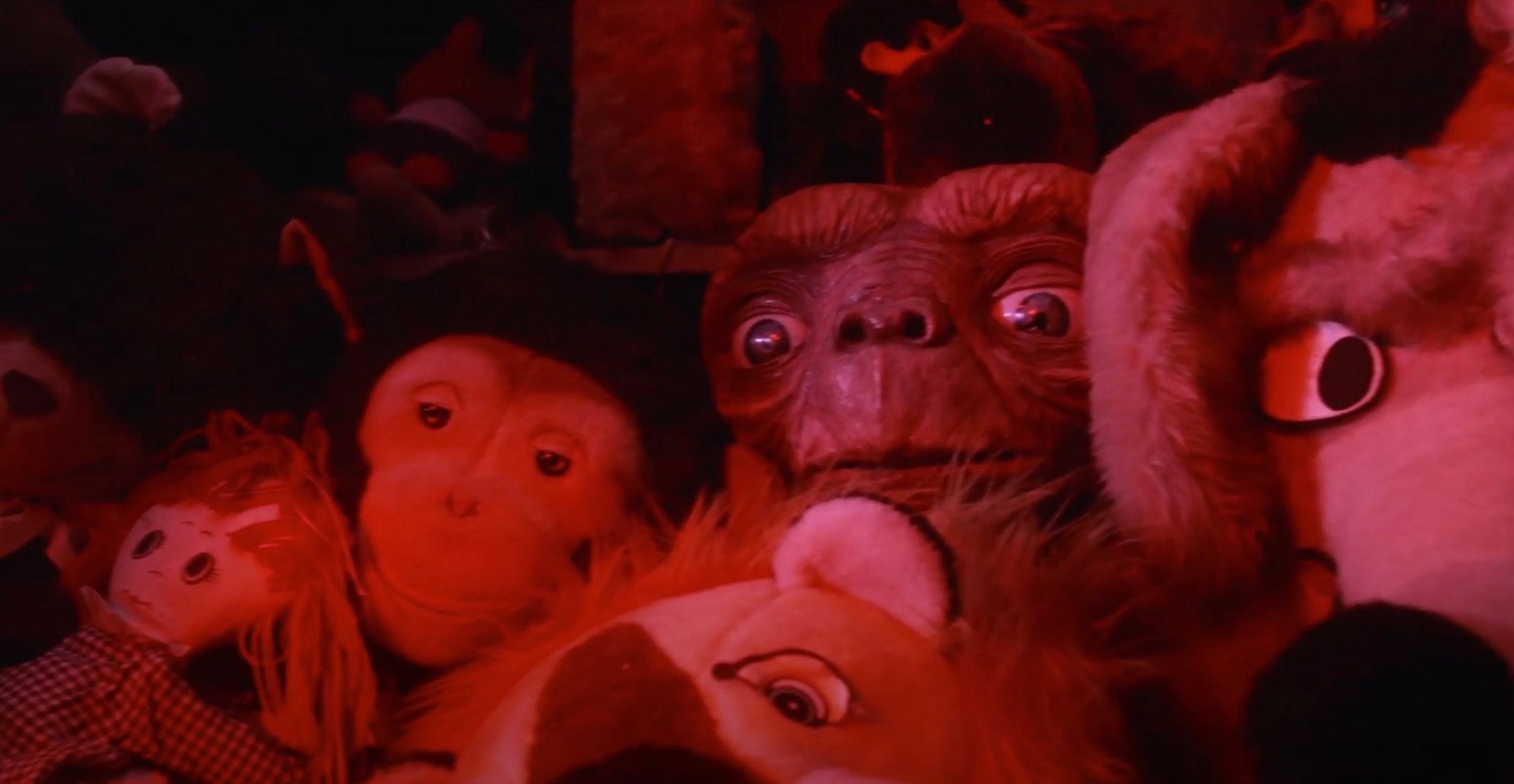 E.T. hiding in a bunch of stuffed animals around him.