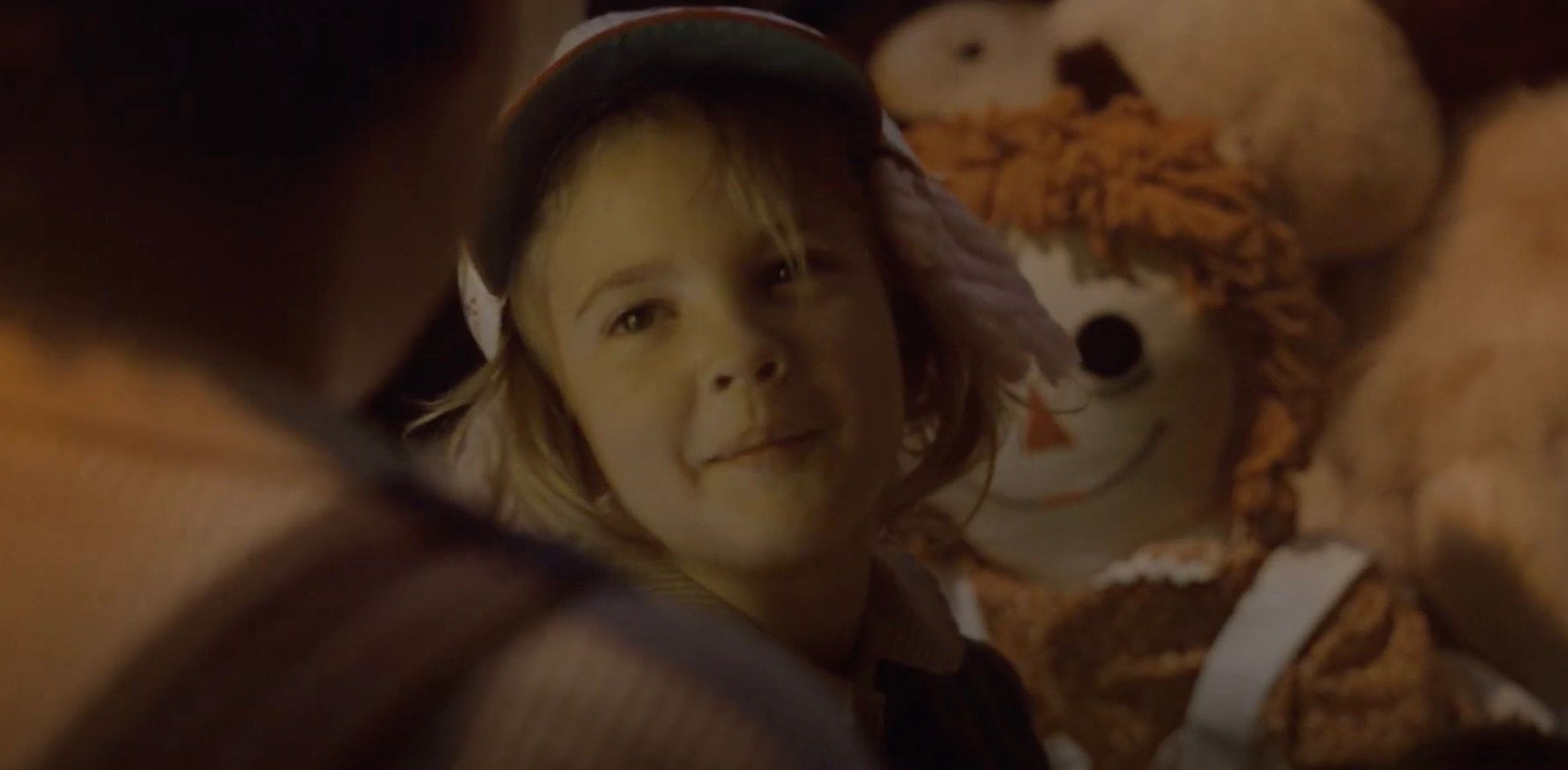 Drew Barrymore as a little girl talking to Elliott with stuffed animals behind her in E.T.