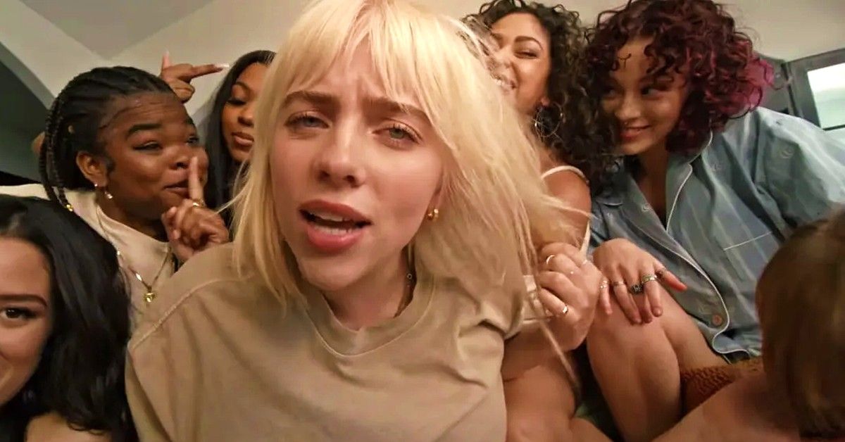 Billie Eilish with blonde hair and tan shirt in group of girls for Lost Cause music video.