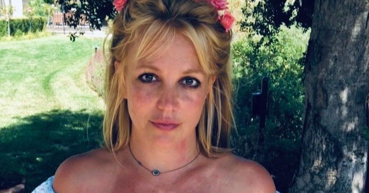 Britney Spears with flower headband standing outside by tree