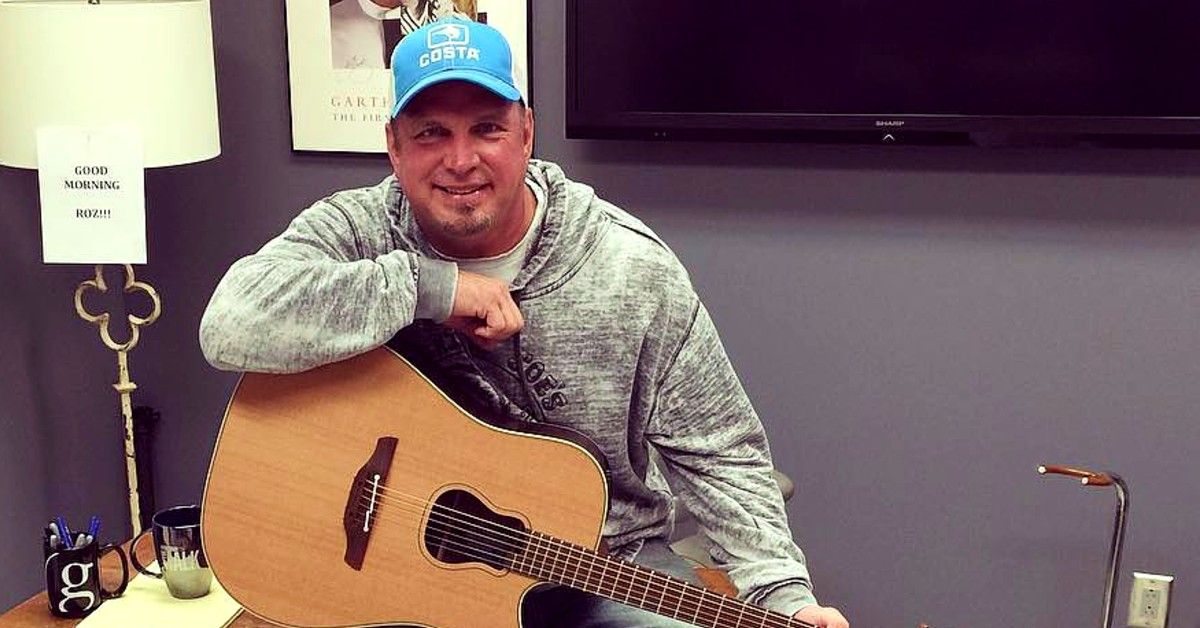 Garth Brooks wearing blue cap and holding guitar