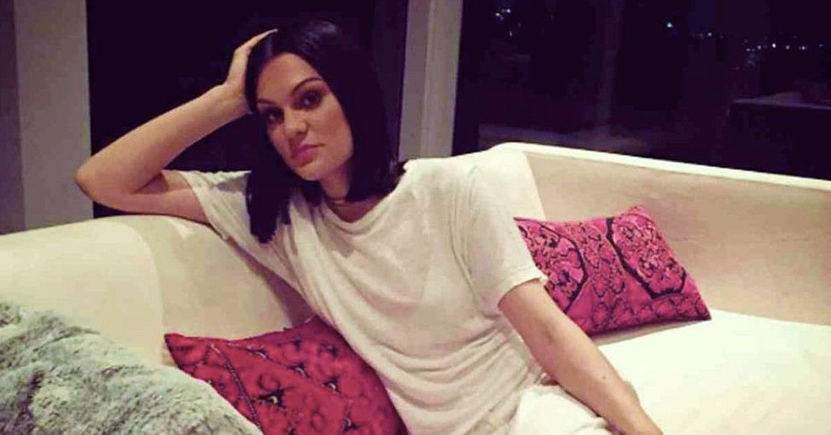 Jessie J in white t-shirt sitting on white couch with pink pillows