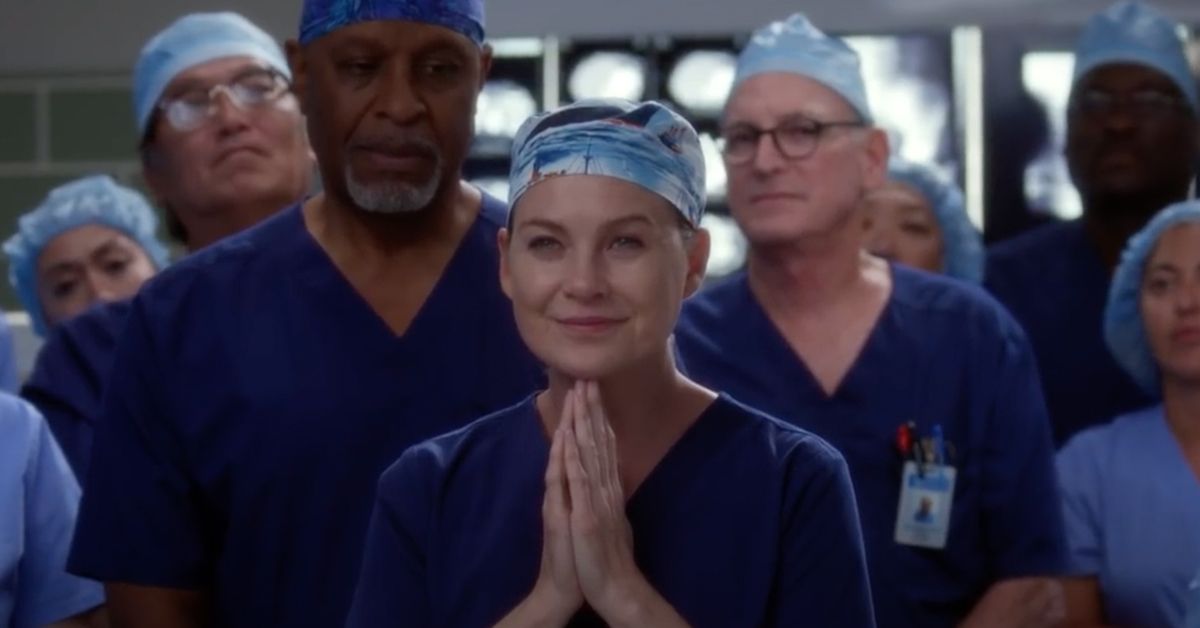 Ellen Pompeo as Meredith Grey in a scene of Grey's Anatomy, praying with other doctors surrounding her.