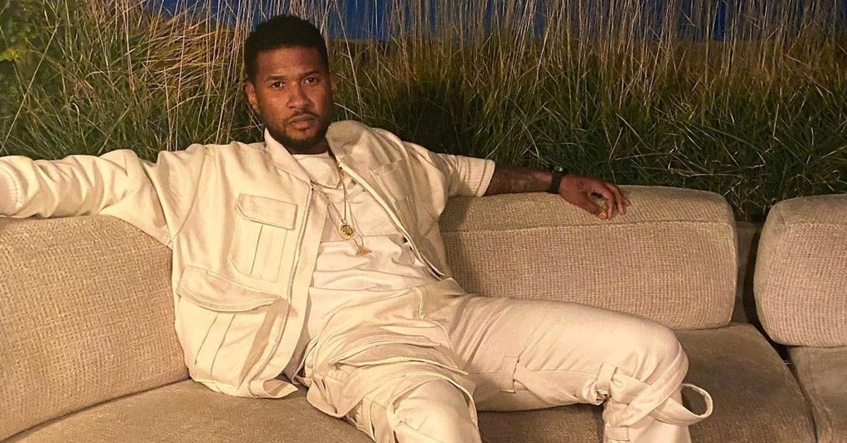 Usher sitting on a couch in white outfit