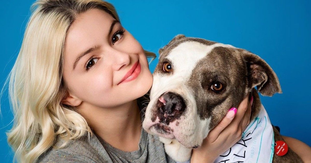 Ariel Winter posed with a pitbull dog in front of blue background