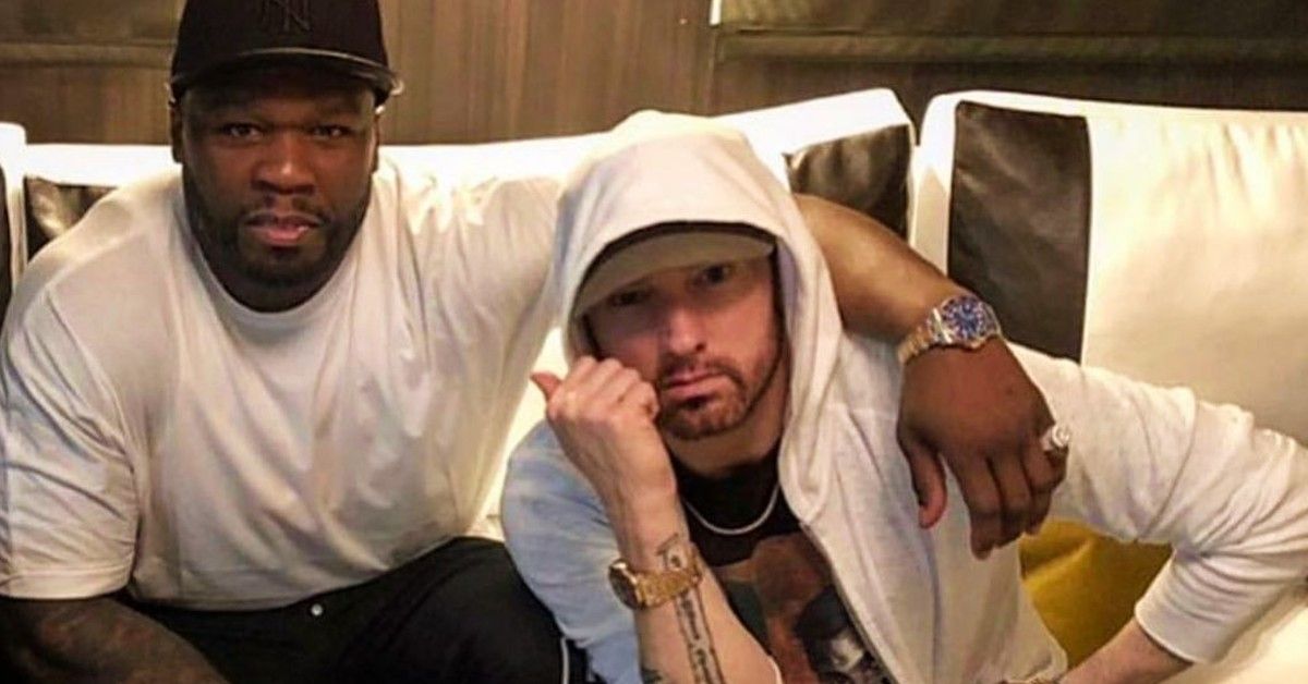 50 Cent and Eminem both wearing white posed together on a couch.