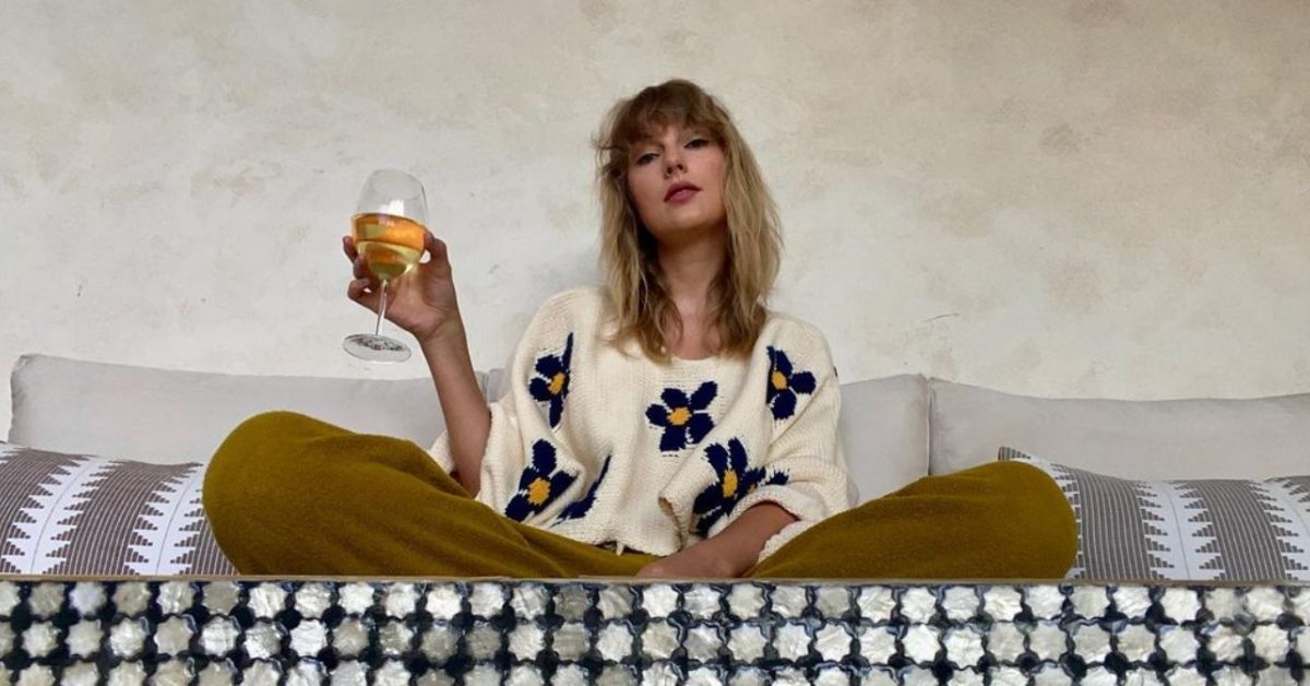 Taylor Swift sitting with glass of wine home sweater