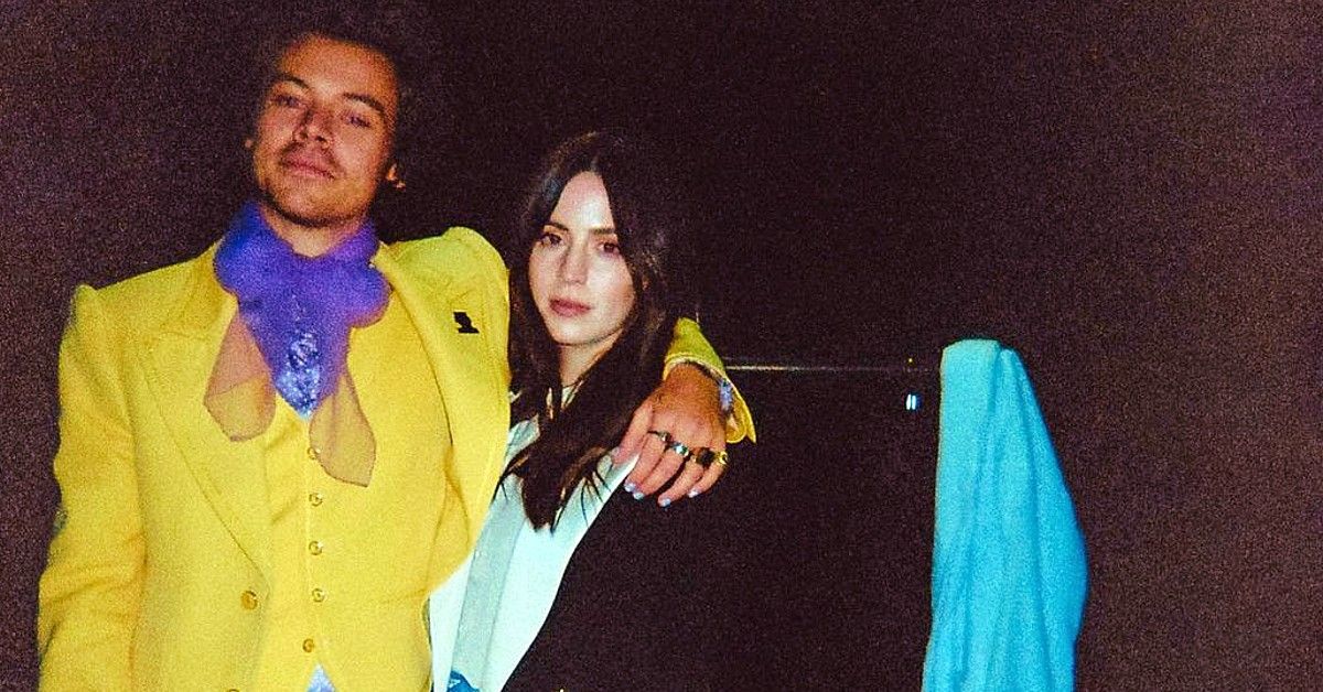 Harry Styles in yellow suit and purple scarf posed with arm around Gemma Styles backstage