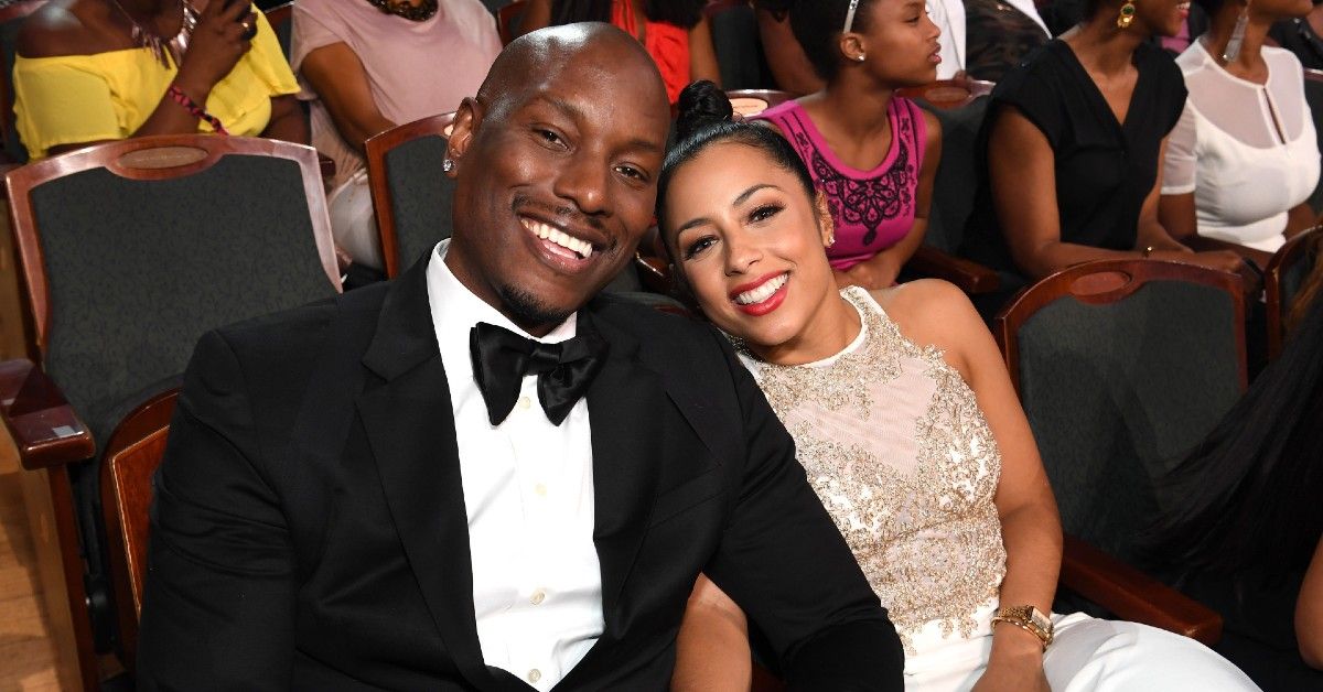 Tyrese Gibson in black and white tuxedo sitting next to Samantha Lee in white laced dress at awards event