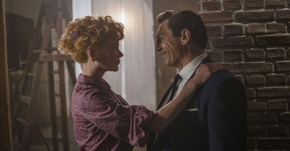 Nicole Kidman and Javier Bardem as Lucille Ball and Desi Arnaz in Being the Ricardos. They are facing one another and Lucille has her hand on Desi's shoulder.