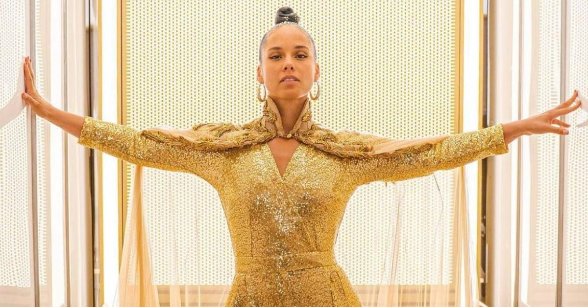 Alicia Keys with her arms out dressed in all gold