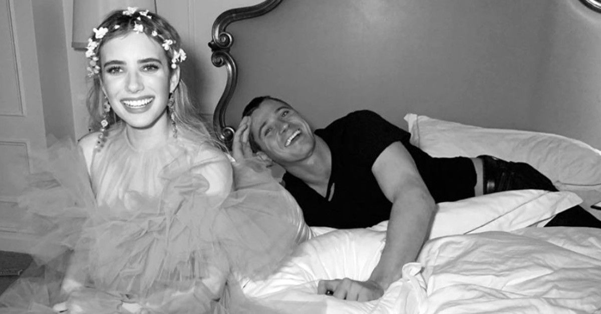 Emma Roberts and Garret Hedlund sit on bed in black and white photo