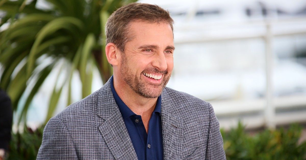 Steve Carell in plaid suit jacket and blue shirt smiling outside