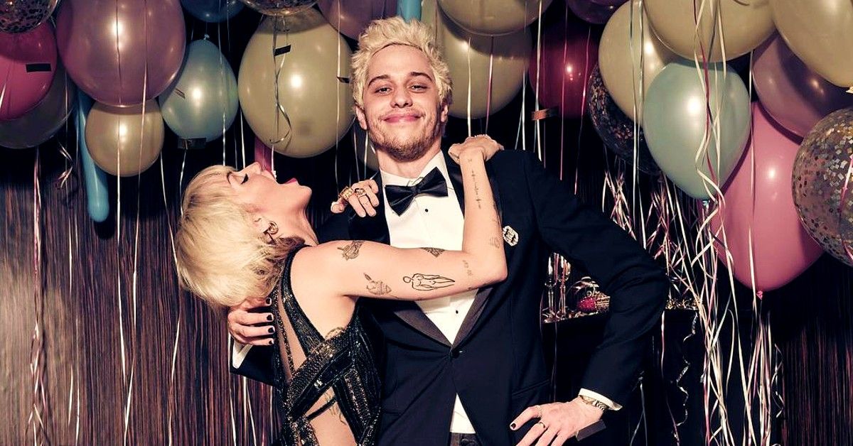 Pete Davidson in tuxedo poses with Miley Cyrus around balloons