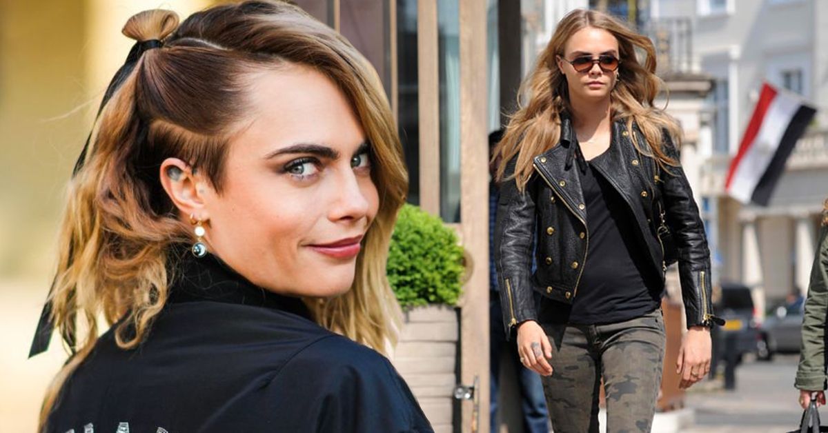 Cara Delevingne smiling at the camera from over her shoulder with her hair tied while wearing a black shirt (front), Cara Delevingne walking in public while wearing a black shirt, leather jacket, tight army pants, and round sunglasses (back)