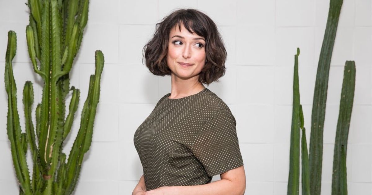 Milana Vayntrub wearing a brown dress 