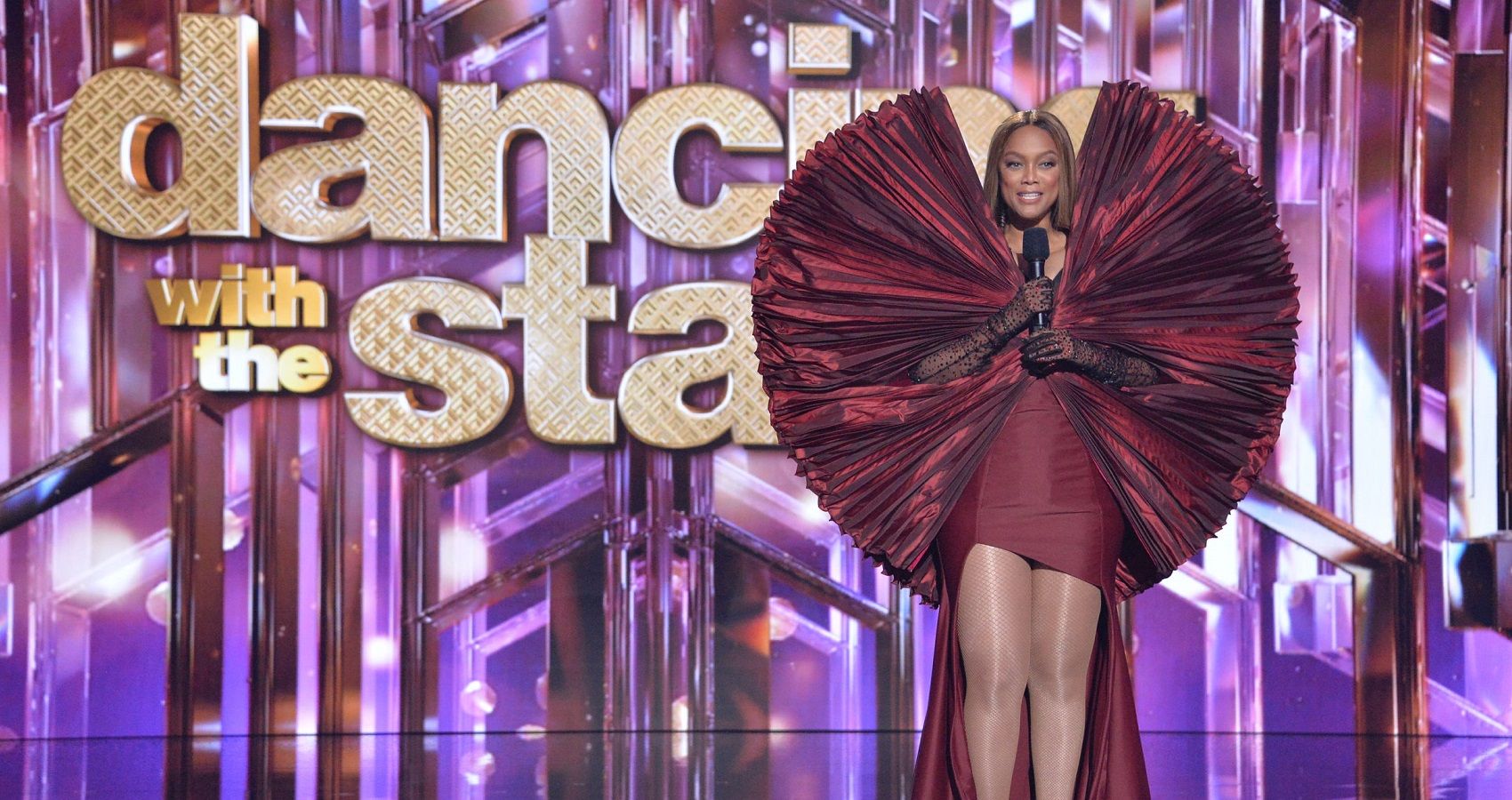 Tyra Banks wearing an elaborate red dress on the Dancing with the Stars stage