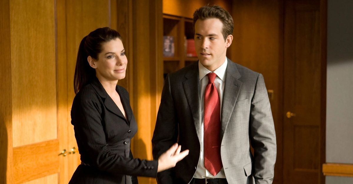 Sandra Bullock and Ryan Reynolds in suits in a office