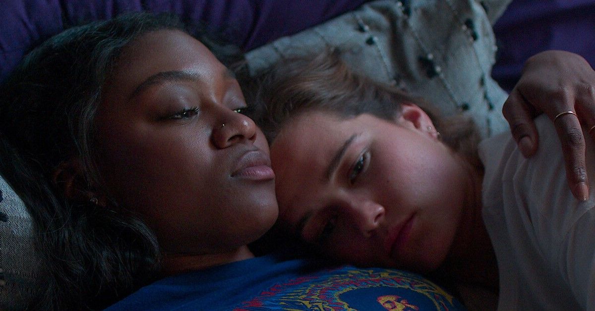 Imani Lewis as Calliope and Sarah Catherine Hook as Juliette in a still from First Kill. Calliope is cuddling Juliette as they both look pensive and sad.
