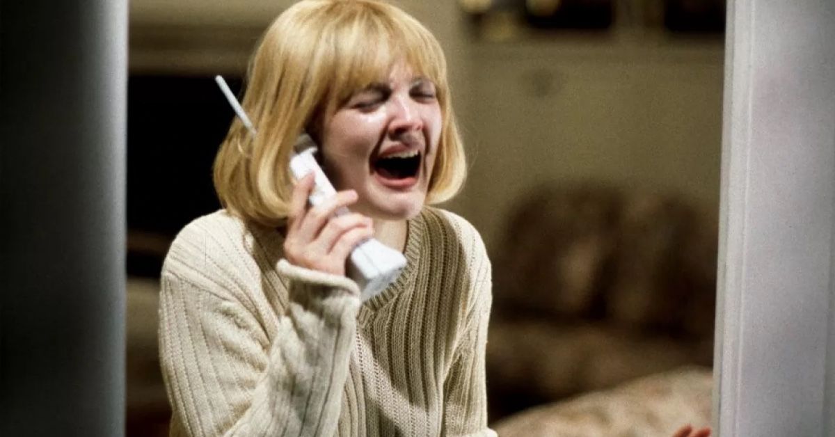 Drew Barrymore screams in fear while holding a phone to her ear as Casey Becker in a scene of Scream.