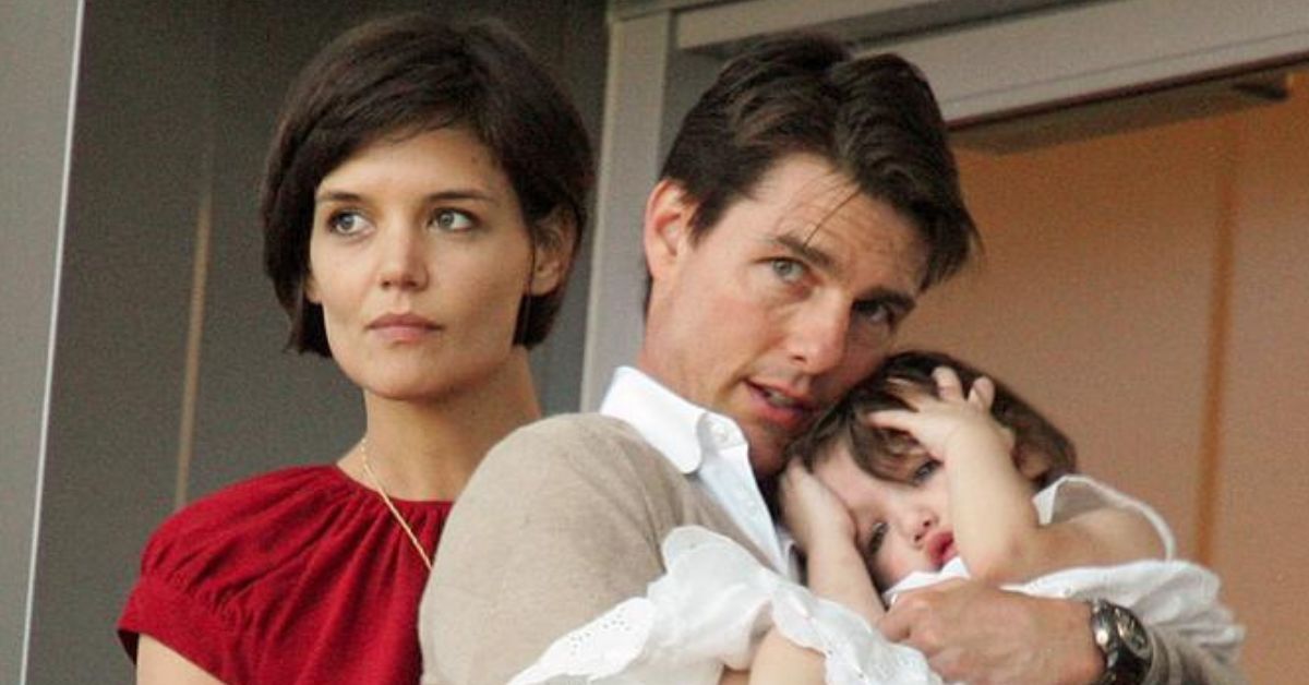 Katie Holmes Short Brunette Hair Looking Away Red Top Gold Necklace Tom Cruise Pensive White Shirt Holding Suri Cruise Hands On Her Head