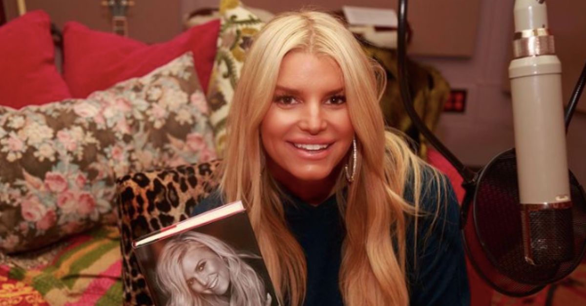 A picture of Jessica Simpson smiling holding a copy of her book Open Book.