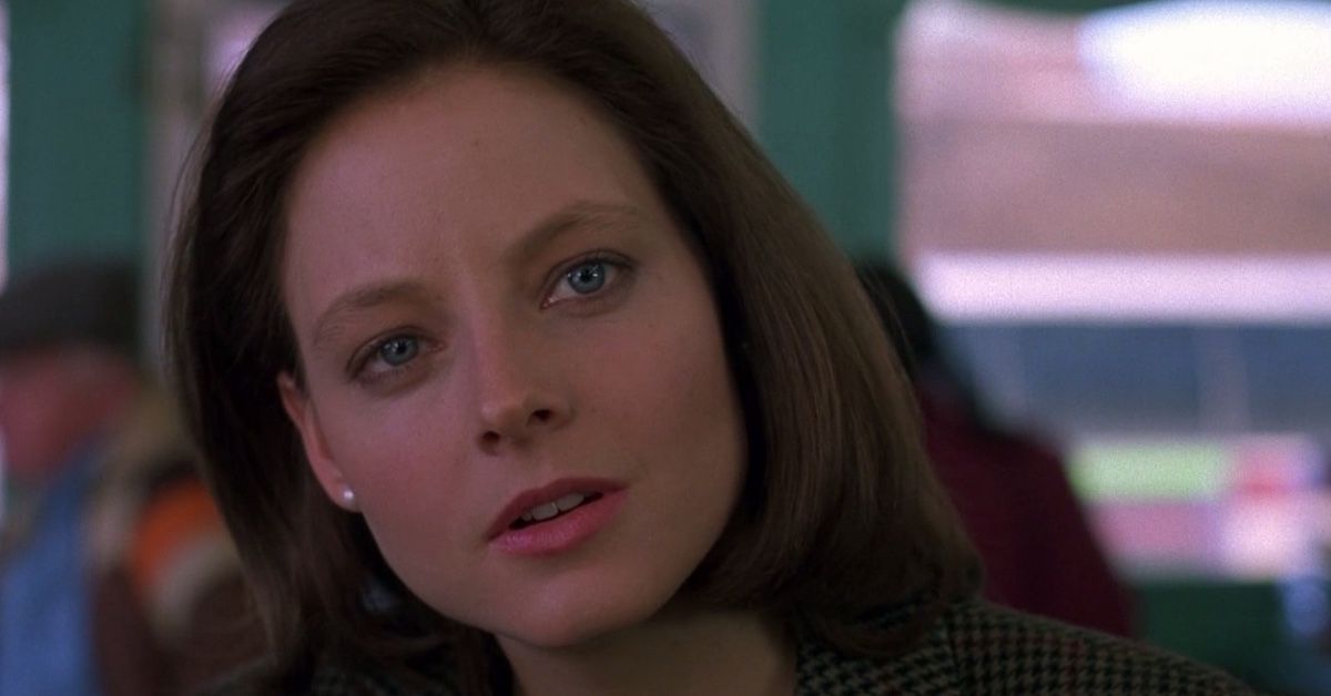 A closeup of actress Jodie Foster as Clarice Starling in The Silence of the Lambs. She has her brown hair in a bob, with one side tucked behind one ear, and is looking pensive, her lips parted.