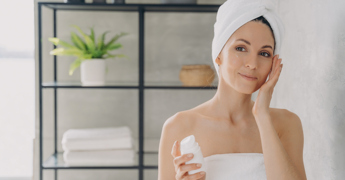 woman in towel putting on face cream