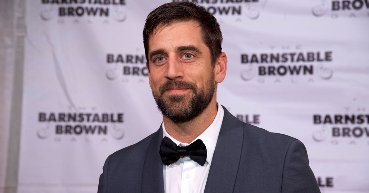 Aaron Rodgers wearing a suit on a red carpet